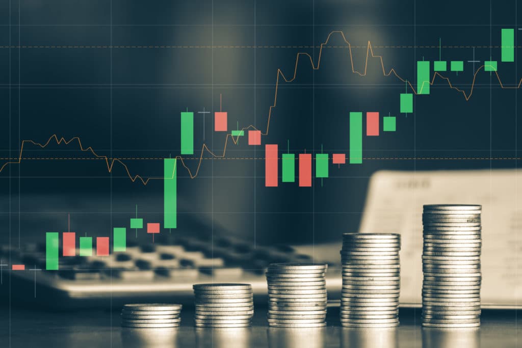 An image with coins stacked up at different heights to show upward movements in exchange rate. An overlay of a line and bar graph is also added to the image to showcase up and down movements of a rate. 