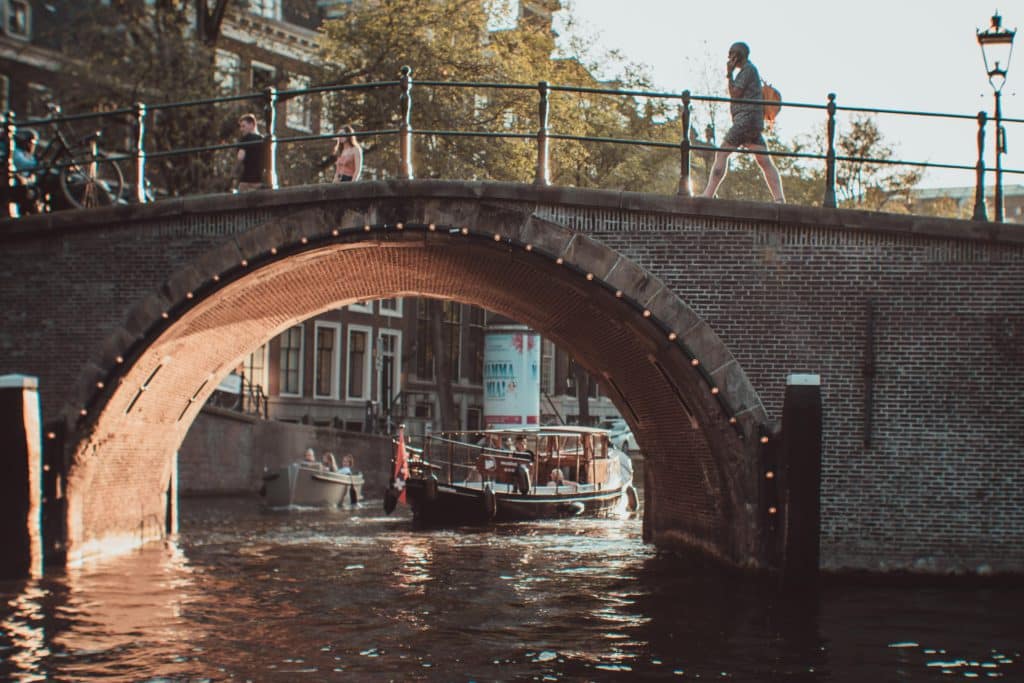 People walking across a bridge over the canals in Amsterdam, Netherlands.