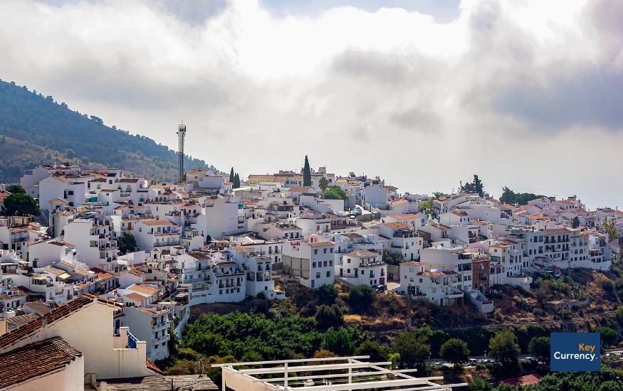 photo of spanish white properties on a hillside on a cloudy day. 
