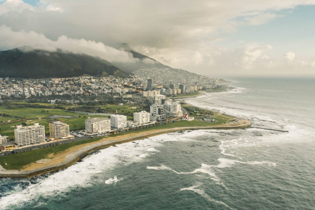 Aerial photo of buildings next to the sea in Cape Town, South Africa, underneath the mountains.