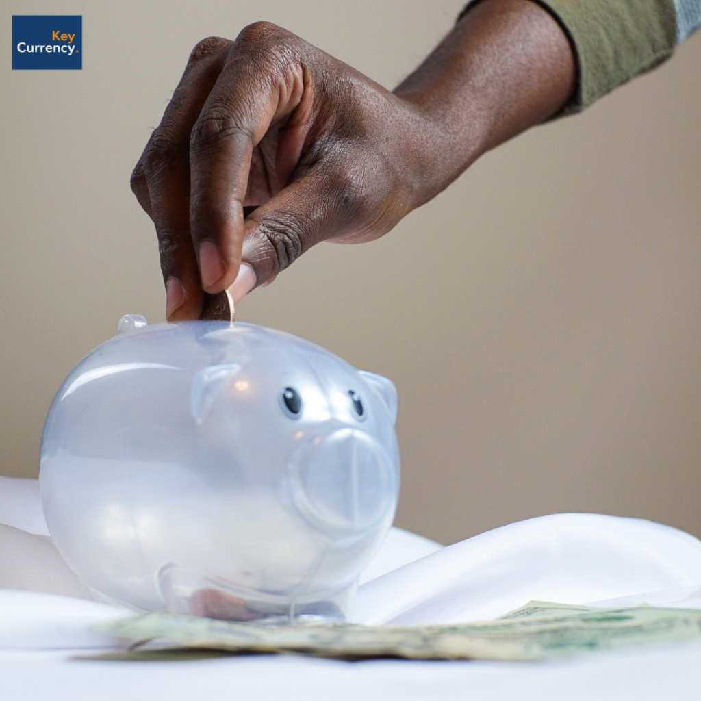 Image showcasing a person placing money into a piggy bank to showcase saving money.