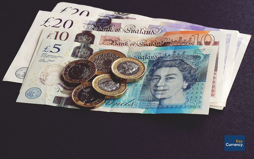 Selection of different pound sterling currency coins and notes on a table. 