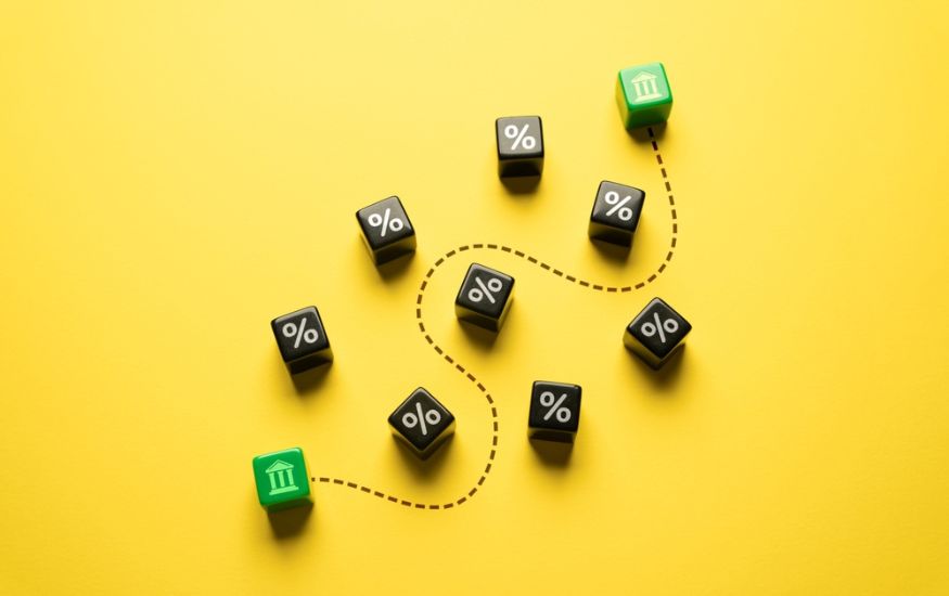 an image joining two banks (green dice) depicting a money transfer. Black dice with % are dotted around to showcase the charges that are involved with an international money transfer process.