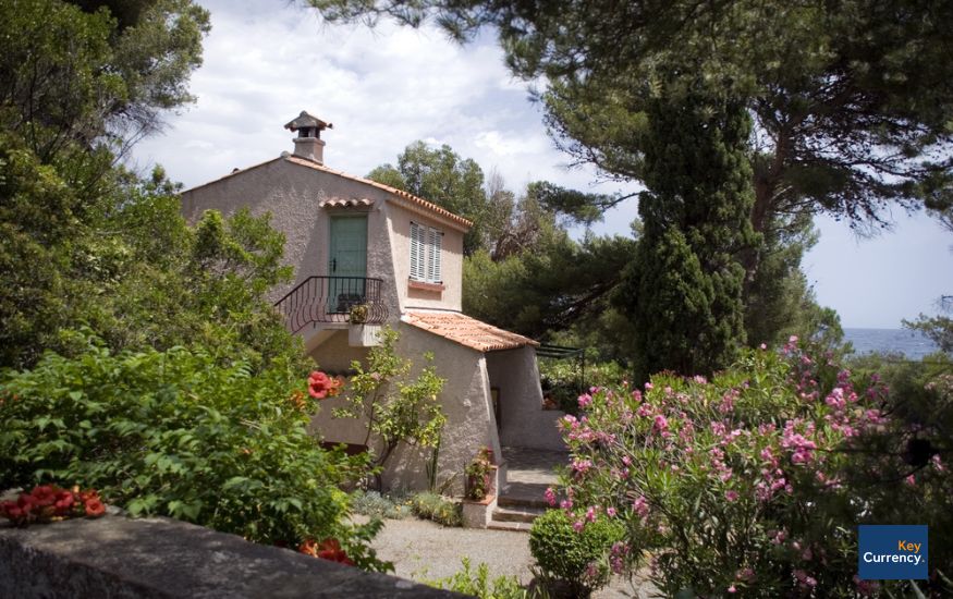 Photo of a property in the French Riviera, surrounded by green trees and colourful flowers. 