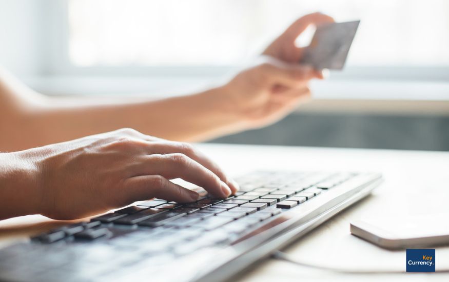 Person putting in bank details online using a computer. Person is also holding their bank card. 