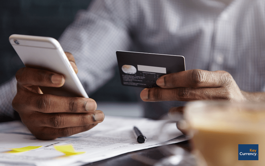 Person holding a mobile and credit card to do online, mobile banking, using an app.